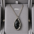 Necklace with a dark pendant in a gray jewelry box