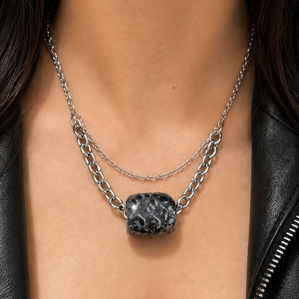 Necklace with a stone pendant worn by a person in a black leather jacket.
